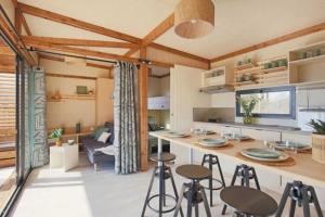 a kitchen and living room with a counter and stools at Camping - Piscine - ccbbdag in Vic-sur-Cère