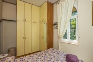 a bedroom with yellow cabinets and a bed and a window at Apartment Roberta in Lovran