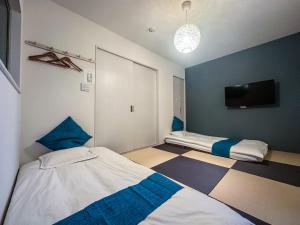 大阪市にあるHANASTAY花渓居 · 楓(KAEDE)のベッド2台と薄型テレビ付きのベッドルーム