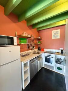 a kitchen with white appliances and an orange wall at La Maisonnette in Templeuve