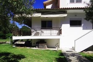 a white house with a balcony and a yard at Kalogeriko in Polychrono