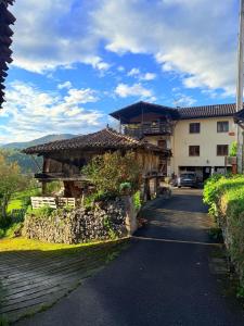 a house with a stone wall next to a street at El Portiellu in Cabielles