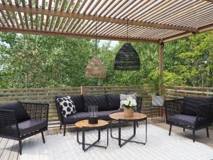a patio with a couch and chairs under a pergola at Social villa near the sea! in Torslanda