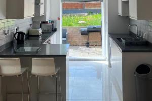 a kitchen with a sink and a counter with stools at Southgate Home - Sleeps 14 - Parking - Central in London