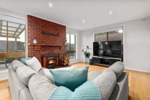 a living room with a couch and a fireplace at Beleura's Beachside Beauty in Mornington