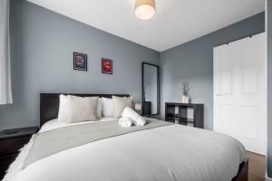 a bedroom with a large white bed with blue walls at 3 Bed Stockport Home by City SuperHost in Manchester