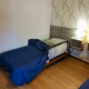 ein kleines Bett mit einer blauen Decke in einem Zimmer in der Unterkunft Gite Les Renardières en Bretagne Romantique proche in Saint-Pierre-de-Plesguen + 19 Fotos