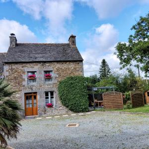 ein Steinhaus mit roten Blumen im Fenster in der Unterkunft Gite Les Renardières en Bretagne Romantique proche in Saint-Pierre-de-Plesguen