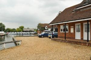 a house with a car parked next to a marina at Rebel in Wroxham +5 photos