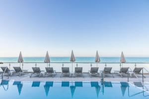 a pool with chairs and umbrellas next to the ocean at Perla Marina in Nerja