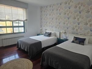 a bedroom with two beds and a window at Winahost Vionta en Primera Línea de Mar in Ribeira