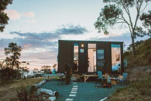 a person standing in front of a tiny house at River Ridge Tiny House by Tiny Away in South Arm