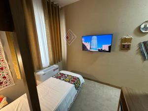希瓦Hotel Byond Khiva的一间小房间，墙上有一张床和一台电视 更多28张照片