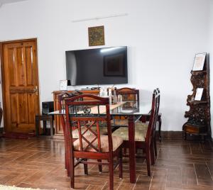 a dining room table with chairs and a television at SkyNest Bhimtal in Rāmgarh