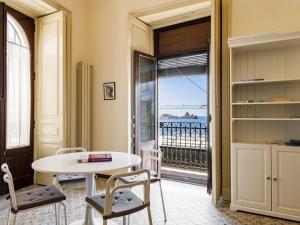 a room with a table and chairs and a balcony at Porticciolo sea view in Aci Castello