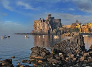 a view of a castle on a rocky shore at Porticciolo sea view in Aci Castello +8 photos