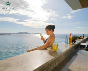 a woman sitting on the edge of a pool with a drink at Apec By Vu Hai Phan Thiet in Mui Ne