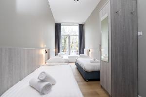 1 dormitorio con 3 camas y espejo en The Crown Hotel, en Ámsterdam