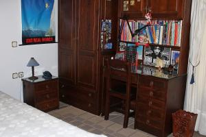 Katoikia me ta Pitharia في برينوس: غرفة نوم مع مكتب ورف كتاب مع كتب