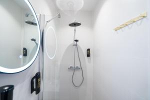 Un baño blanco con ducha y espejo. en The Crown Hotel, en Ámsterdam