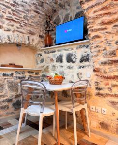 a table with two chairs and a tv on a stone wall at Vilitsa Holiday House in Pyrgi