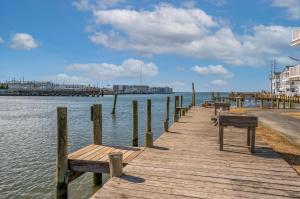 a wooden dock with benches on a body of water at Ducks, Docks, And Flip Flops in Chincoteague