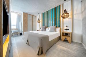 a bedroom with a large white bed and a chair at HOVIMA Suites Costa Adeje in Adeje