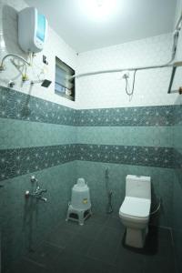 a bathroom with a toilet and a shower in it at Hotel Pergola - Mysore in Chāmundi