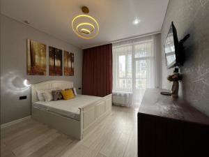 a bedroom with a bed and a television in it at Respublika LUX Уютная 2-комнатная квартира in Astana