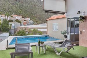 Un patio con mesa y sillas y una piscina. en Casa Haroldo, en Candelaria