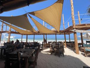 a restaurant on the beach with tables and umbrellas at Lapili Residence in Kiwengwa