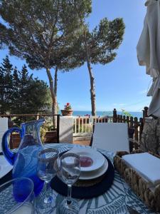 a table with a blue vase and plates and glasses at Villa Fiorella in Sperlonga