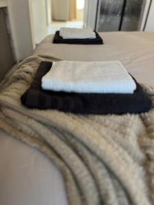 two beds with white and black towels on them at Logement cosy & atypique à l'étage d'une maison, entrée indépendante, proche de Paris in Bonneuil-sur-Marne