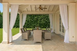una sala da pranzo con tavolo e sedie su un patio di Villa Forte Dei Marmi, Pool & Garden a Forte dei Marmi