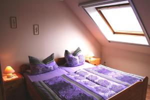 1 dormitorio con cama morada y ventana en Haus Wiesengrund, en Werdum