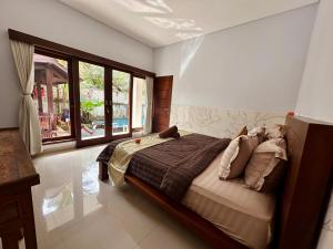 una camera da letto con un letto e una grande finestra di Kanda Villa ad Ubud