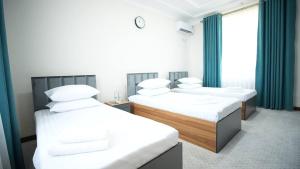 two beds in a room with green curtains at Bmb Village Jizzakh Hotel in Dzhailʼma +16 photos
