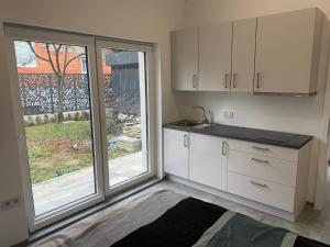 a kitchen with white cabinets and a large window at Villa Aldina Apartment 2 in Bihać