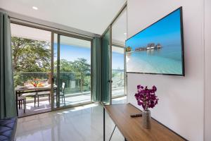 a room with glass doors and a table with a vase of flowers at Sea View Apartment A32 in Kamala Ocean Residence just 450m from Kamala Beach in Kamala Beach