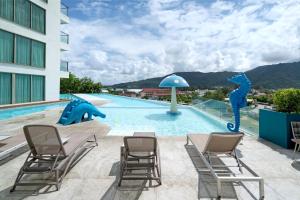 a pool at a hotel with chairs and a slide at Sea View Apartment A32 in Kamala Ocean Residence just 450m from Kamala Beach in Kamala Beach