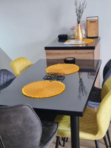 a dining room table with yellow chairs and a black table with yellow plates at Be POZITIVE in Sombor +9 photos