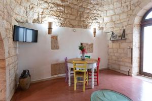 a table and chairs in a room with a stone wall at Trullo Franza - Salento Reservation in Torre Suda