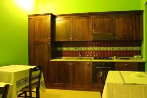 a kitchen with wooden cabinets and a green wall at Sunset affittacamere in Cannole