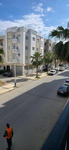 a man in an orange shirt walking down a street at Martil Plage Piscine Fibre & Netflix in Martil