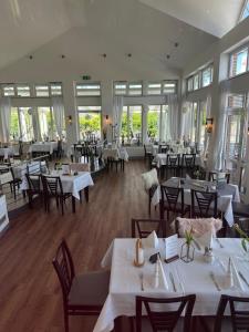 a restaurant with white tables and chairs and windows at Kanal-Haus "Das Gästehaus direkt am Nord-Ostsee-Kanal" in Osterrönfeld