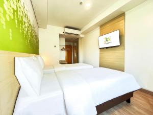 a bedroom with two beds and a tv on the wall at Zest Ambon by Swiss-Belhotel International in Ambon