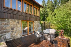 a wooden deck with chairs and a house at Kuća za odmor “Dobra” - Skrad, Gorski kotar in Skrad
