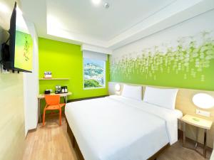 a bedroom with a white bed and a green wall at Zest Ambon by Swiss-Belhotel International in Ambon