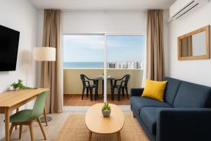 salon z niebieską kanapą i stołem w obiekcie BenalBeach Premium Apartments by Alfresco Stays w mieście Benalmádena