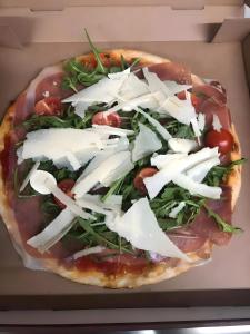 a pizza with cheese and greens in a box at Apartment Ballova in Balve